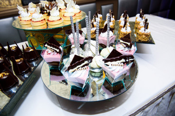 Glasses with cold pink and chocolate desserts stand on mirror tr