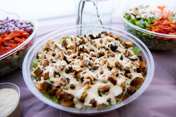 Salad under white sauce served in plastic bowl