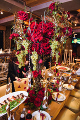 Large bouquet of scarlet roses stands on yellow dinner table