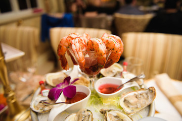 Shrimps in cocktail glass stand on dinner plate with mussels