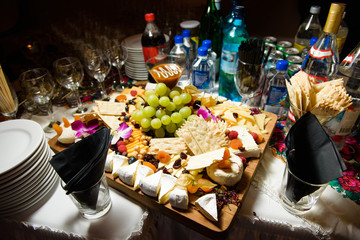 Cut cheese, berries and fruits stand on wooden dish