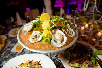 Mussels stand on ice with lemon on large plate