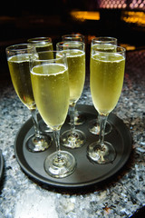 Glasses with champagne stand on little black tray