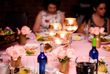 Golden glasses with candles inside stand on pink table