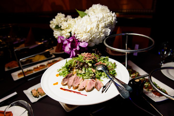 Plate with meat and salad stands on tired dish