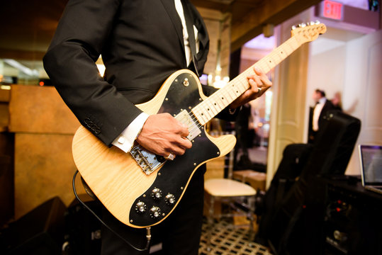 Man in black suit plays a guitar