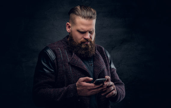 Bearded  male texting an SMS on a smartphone.