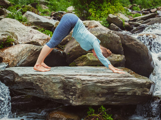 Young sporty fit woman doing yoga oudoors at tropical waterfall