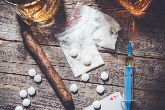 Hard drugs and alcohol on an old wooden table. Close up