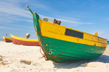 Fishing boat at baltic sea sandy beach with dramatic sky during summertime in Poland