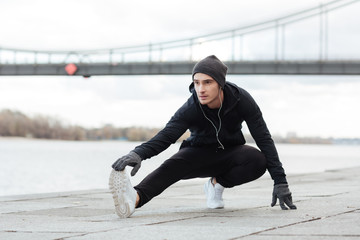 Man athlete listening to music and working out outdoors