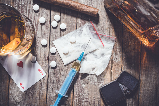 Hard drugs and alcohol on an old wooden table. Close up
