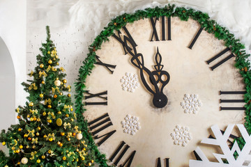 Closeup image of decorated Christmas tree at wall with big clock