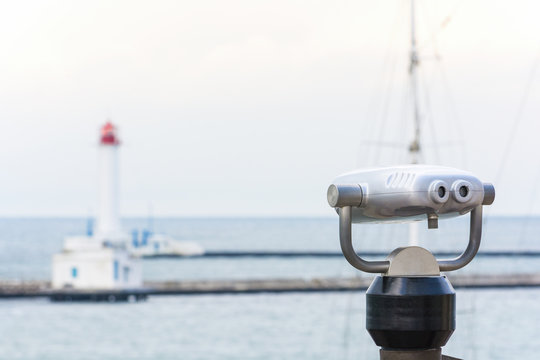 Binoculars in the port. Blurred lighthouse. Sea.