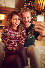 Couple photographing Christmas selfie together