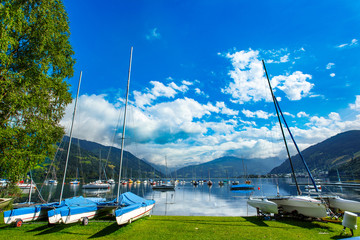 Rent-a-boat service in park. Panoramic view of Zeller See lake. Zell Am See, Austria, Europe. Boats on shore and in water. Alps at background.