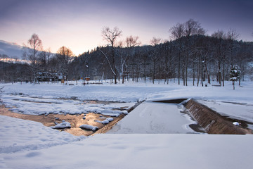 Zachód słońca zimą w górach w mieście górskim Muszyna. Nad potokiem Szczawnik. - obrazy, fototapety, plakaty