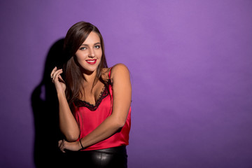 Beautiful model woman demonstrating her gorgeous brown hair while posing for photographer isolated on violet background in studio.