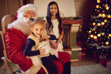 Fototapeta na wymiar Happy little girl in Santa Claus lap