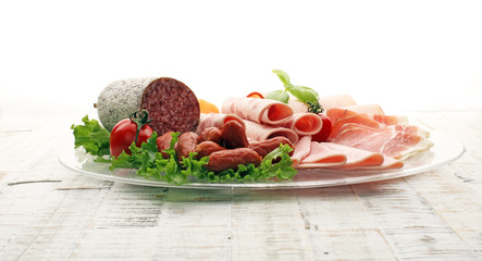 Food tray with delicious salami, pieces of sliced ham, sausage, tomatoes, salad and vegetable - Meat platter with selection - Cutting sausage and cured meat on a celebratory table.
