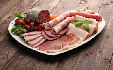 Food tray with delicious salami, pieces of sliced ham, sausage, tomatoes, salad and vegetable - Meat platter with selection