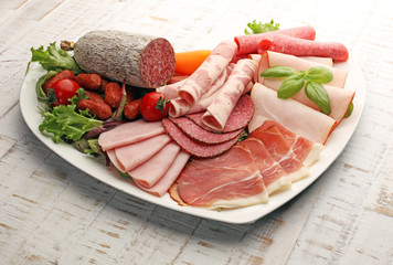 Food tray with delicious salami, pieces of sliced ham, sausage, tomatoes, salad and vegetable - Meat platter with selection