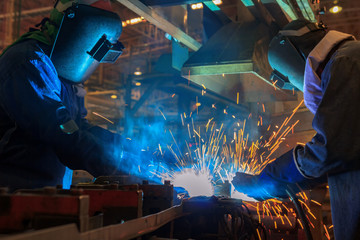 Industrial Workers at the factory are welding  automotive part 
