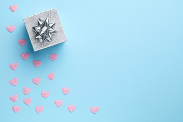 Blue plain background with silver gift and pink hearts