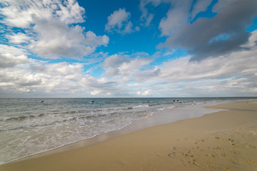 Fototapeta na wymiar The Indian Ocean laps gently onto the white sandy shore of beautiful beach near Busselton, South Western Australia protected by Geographe Bay on a blue sky and white cloud afternoon in early summer.