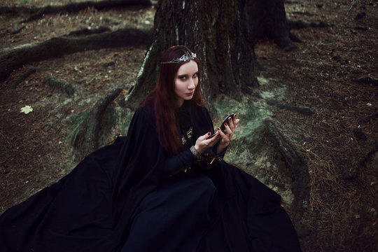 Young beautiful and mysterious woman image of forest elf or witch, looking in the mirror