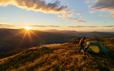 A hiker camping on the mountain summit of Place Fell in the Lake District. UK