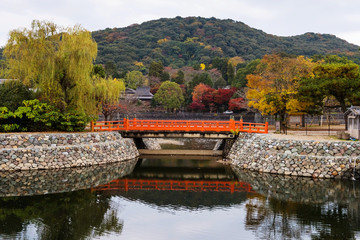 Fototapeta premium Red bridge at Uji River with autumn colors, Kyoto