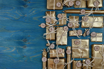 Border of advent calendar with twenty four golden presents on teal wood with negative space to the left