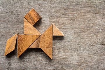 Wooden tangram as man ride the horse shape on old wood backgroun