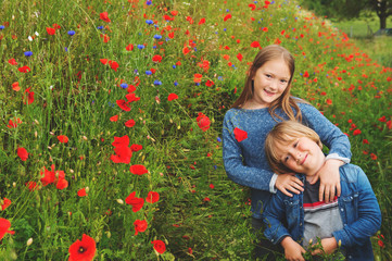 Outdoor portrait of two cute kids playing in poppy field