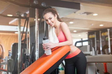 Fototapeta na wymiar Happy sportswoman with bottle of water on training in gym
