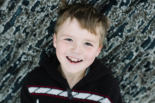 Portrait of boy, smiling, leaning against rocks