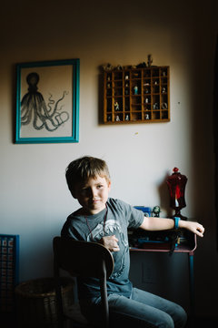 Portrait of boy sitting at desk in bedroom, pensive expression