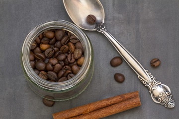 Closeup of freshly roasted coffee beans in a glass jar on a ston