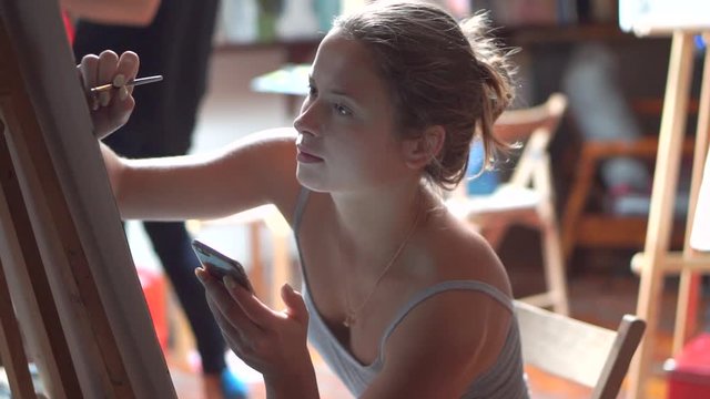 Female artist paints on canvas in workshop