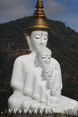 sitting white buddha statue well alignment in front of mountain in thailand