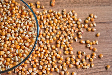 Popcorn kernels on a bowl on a wooden table