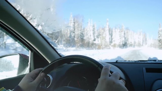 Man's hands of a driver on steering wheel on winter landscape outdoors in slow motion. 1920x1080