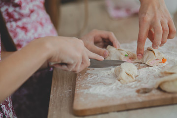 Mother with her daughter are preparing the buns