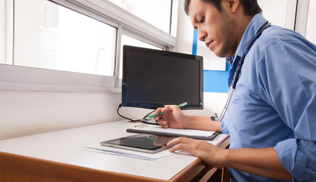 Doctor working at desk in the hospital with his computer.