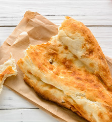 broken half pita bread caucasian, lying on a cutting board. Light wood background.