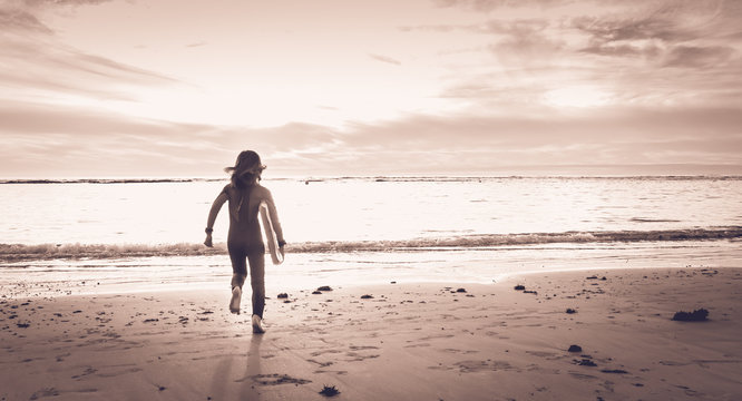 Girl Dressed In A Wetsuit Runs On The Beach