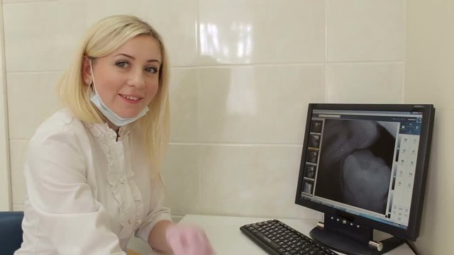 Portrait of female dentist with teeth x-ray on screen.