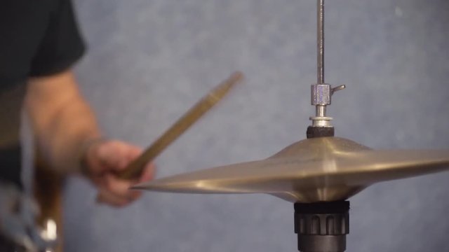Male hands playing on hi hat close up details. Guy beats rhythm on drum set indoor holding drumsticks