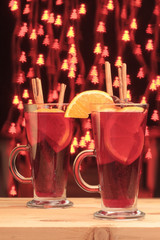 Glasses of Christmas mulled wine on a wooden table with Christmas bokeh on a background